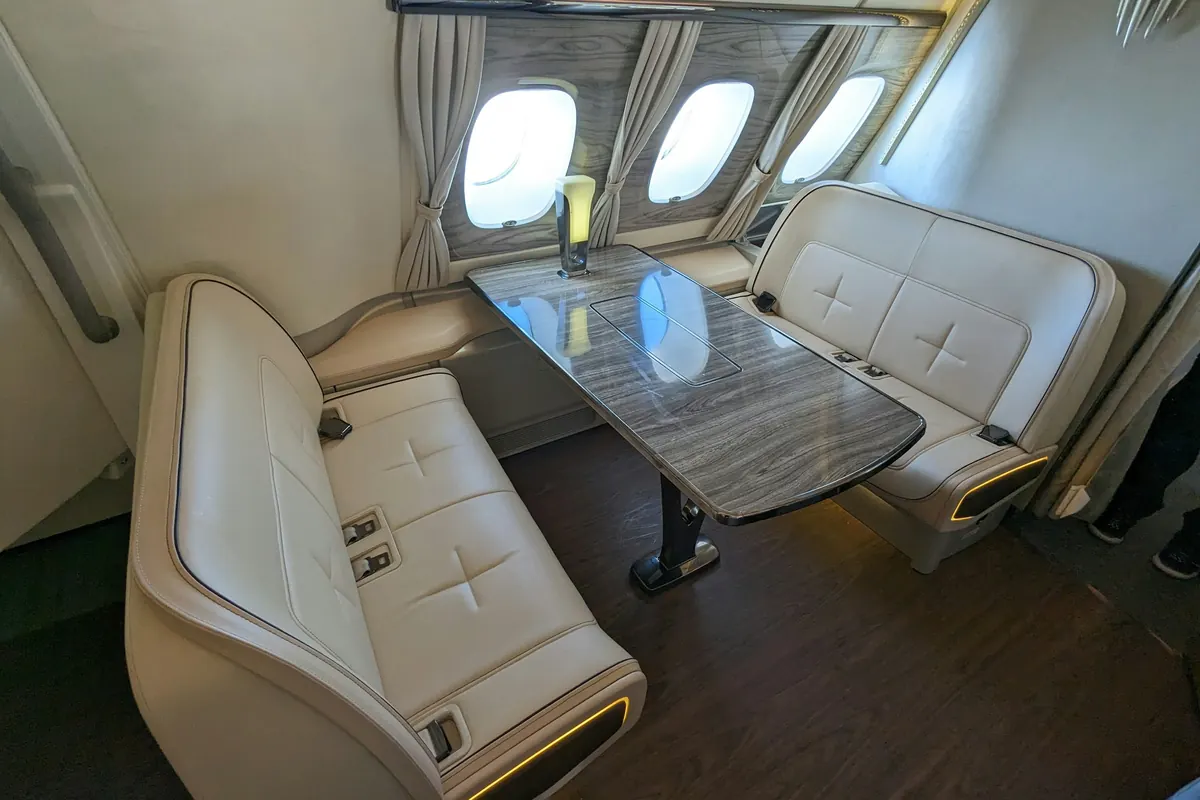Cream leather club seats facing a table in a large private jet cabin