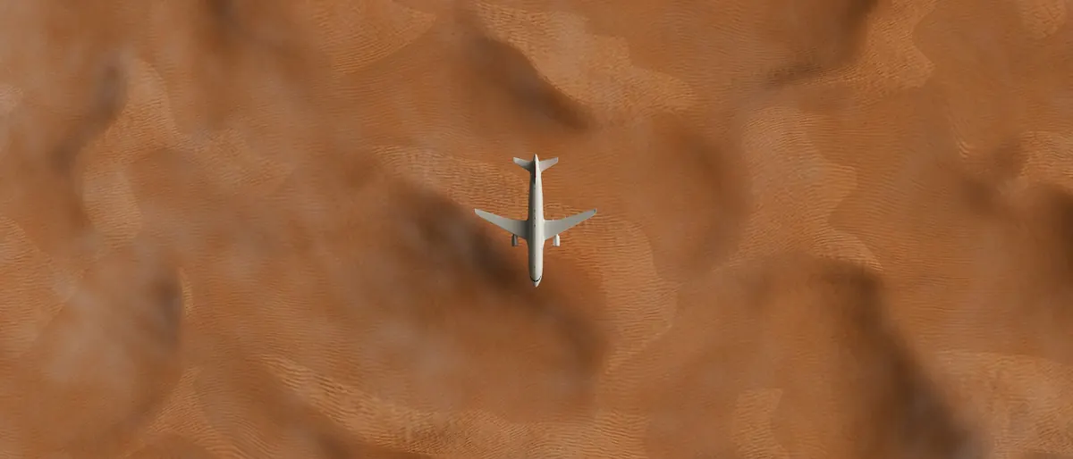 A business jet crossing rippled desert dunes, seen from above