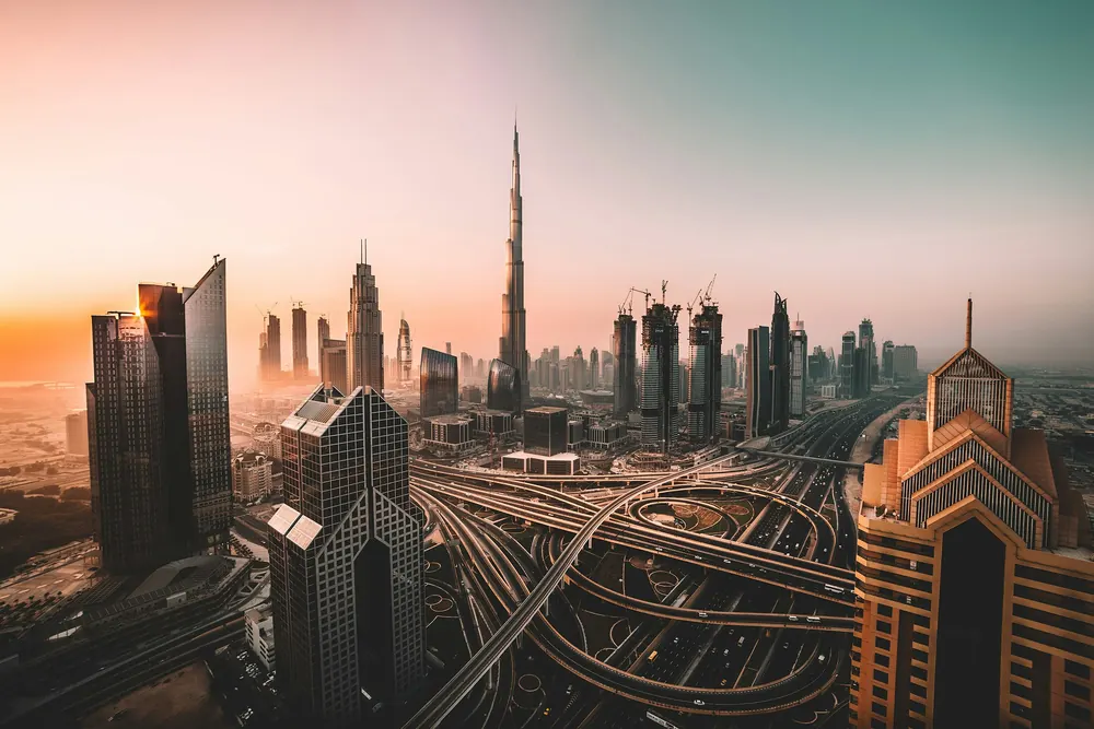 Dubai skyline at sunrise with the Burj Khalifa above a haze of towers and highways