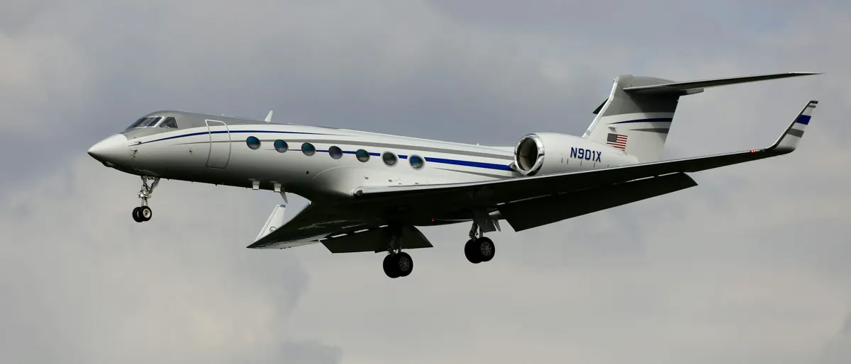 A long range business jet in flight with its landing gear down