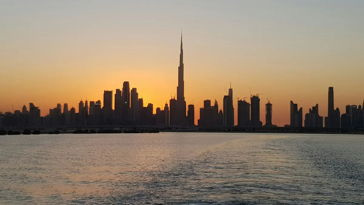 Dubai skyline silhouetted at sunset across the water